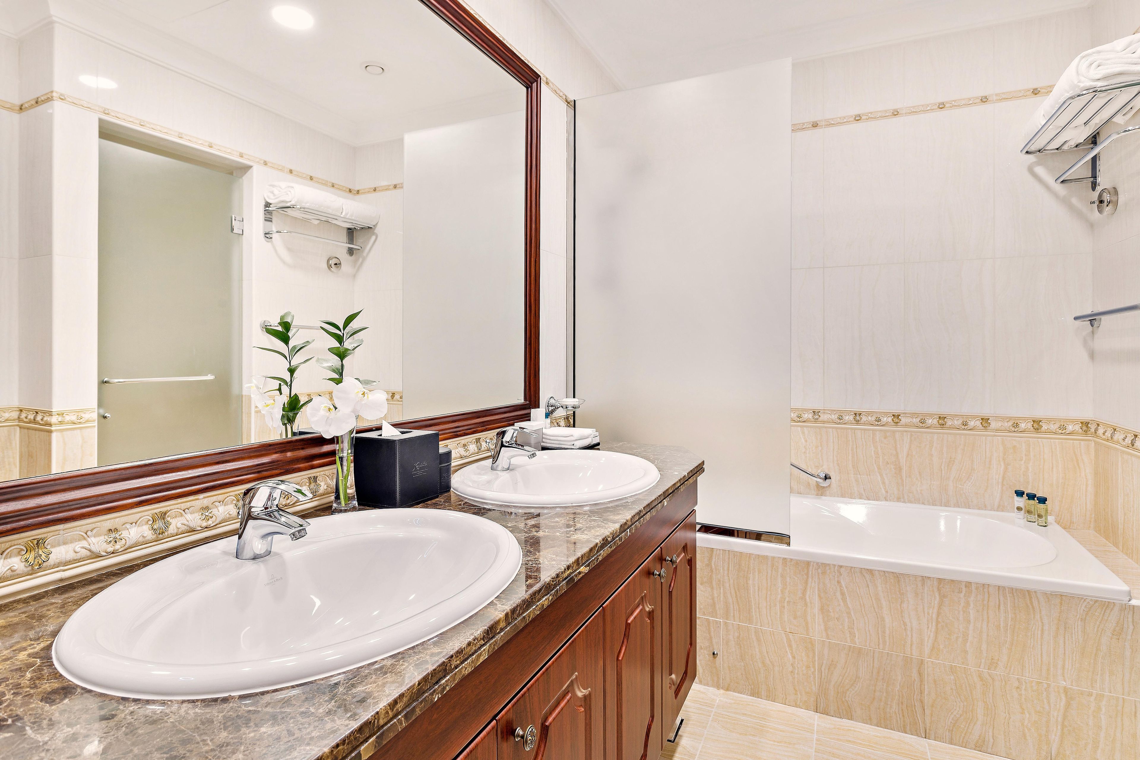 A bathroom with two sinks, a large mirror, and a bathtub.