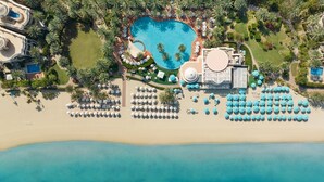 Vista aérea de un complejo turístico con una piscina en forma de corazón, una zona de playa con sombrillas y un edificio grande.