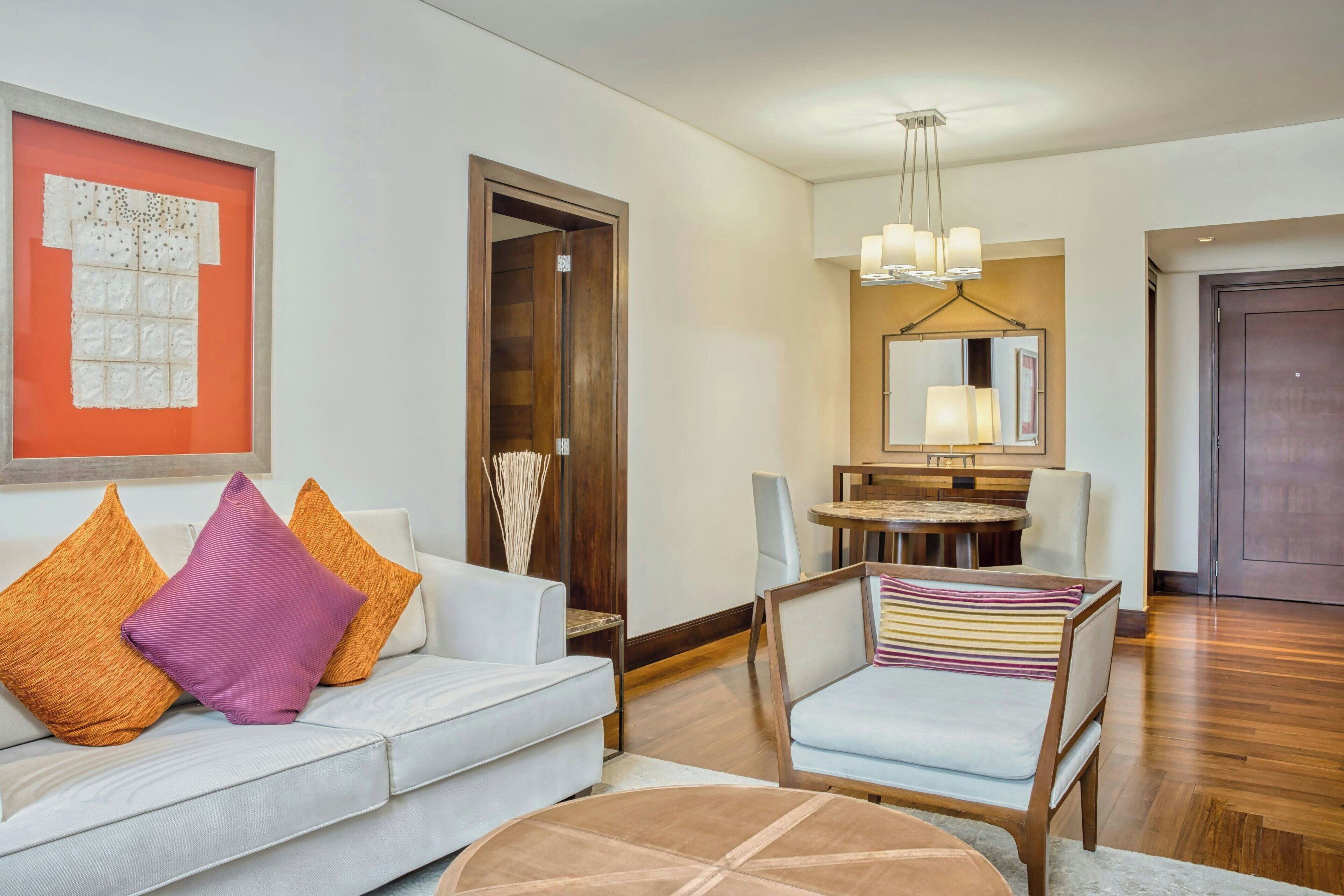 Una sala de estar moderna con un sofá blanco, una mesa de centro redonda y un comedor con una araña.