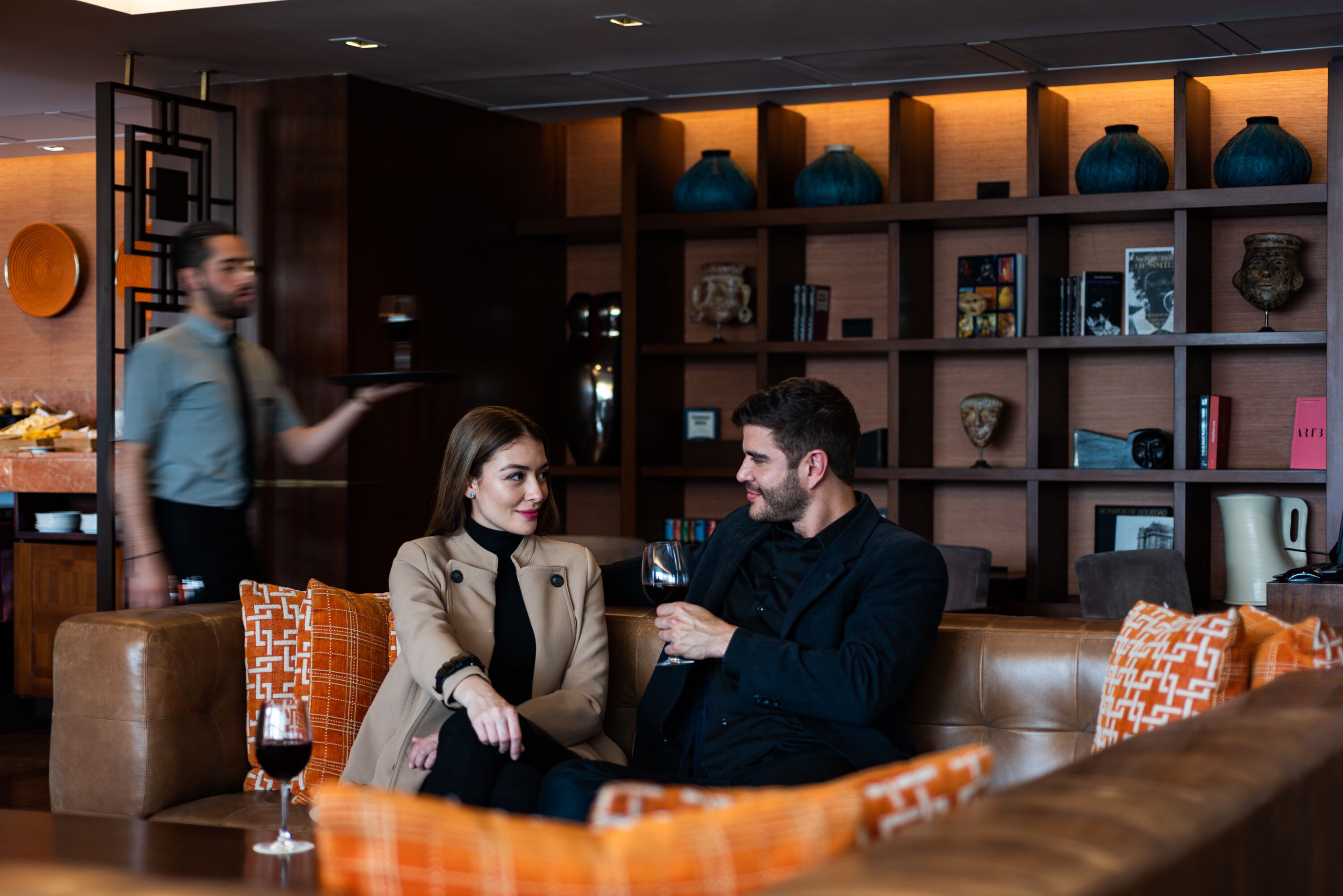 A modern interior with leather sofas, a bookshelf, and decorative vases.