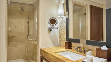 Une salle de bain dotée d’une douche à parois de verre, d’un lavabo avec un plan de toilette en marbre, d’un miroir et d’un meuble-lavabo en bois.
