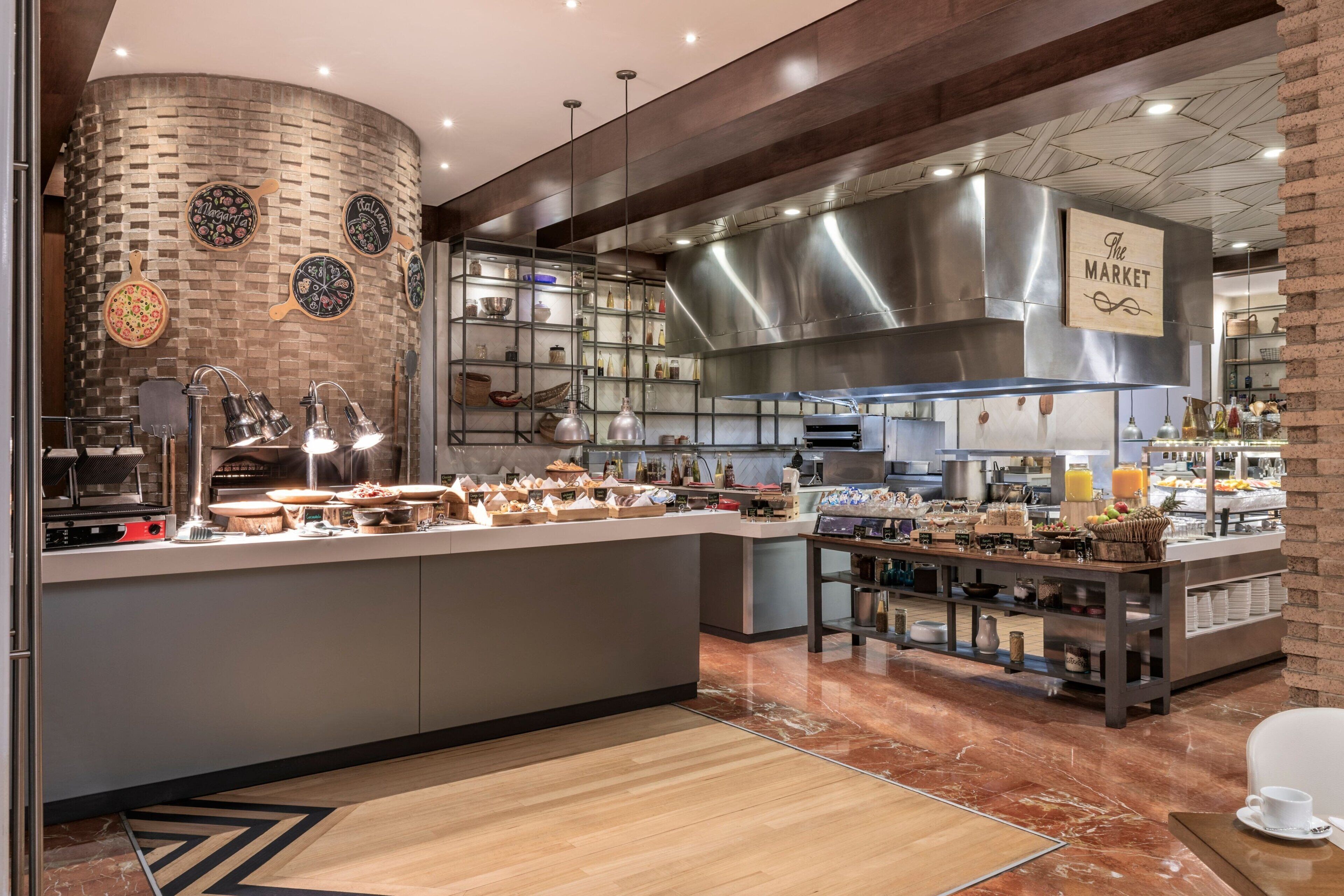 A modern kitchen with a central island, a brick wall with pizza-themed decorations, and a sign reading "The Market".
