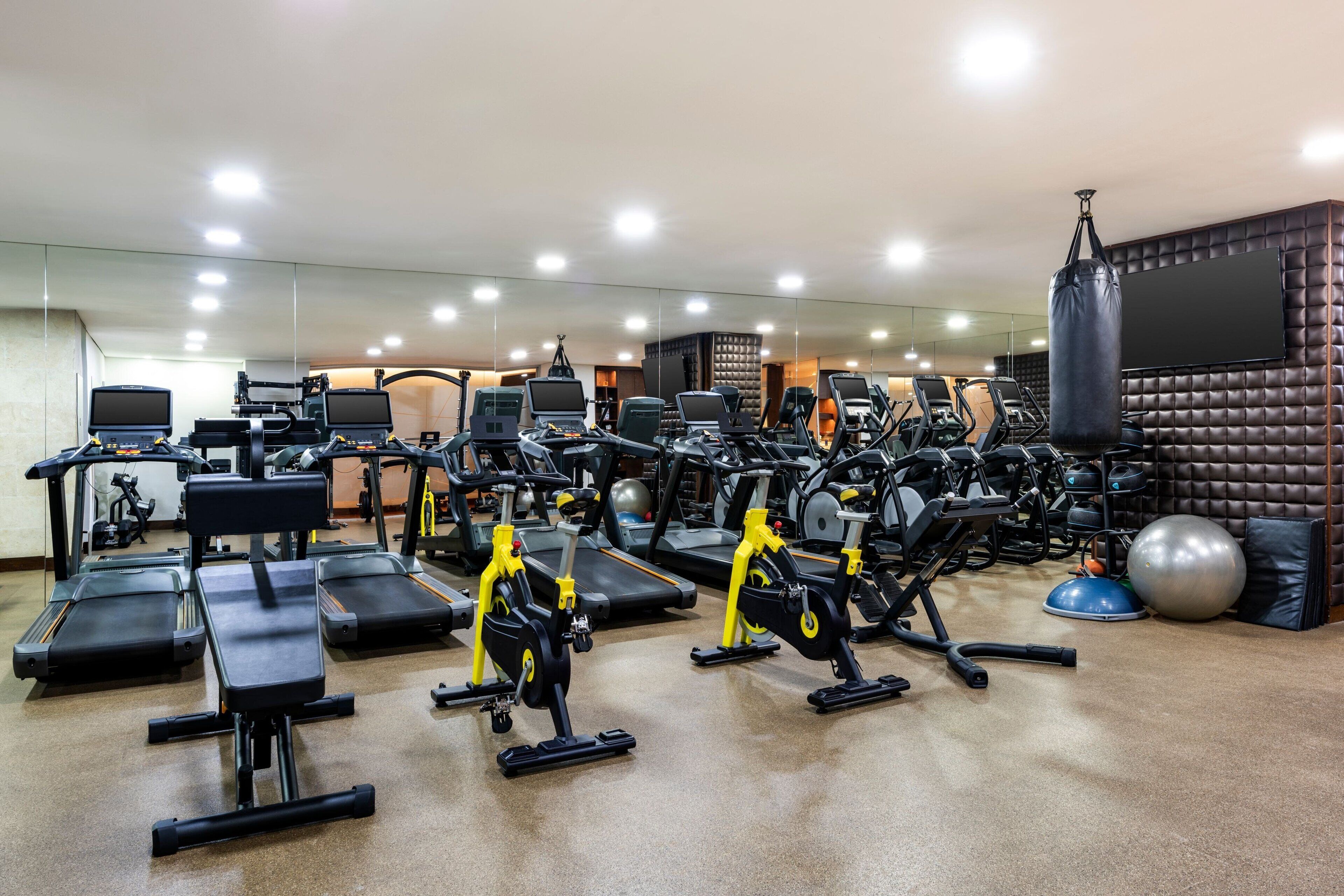 Un gimnasio con diversos equipos de ejercicio, incluyendo cintas de correr, bicicletas estáticas y máquinas de pesas.