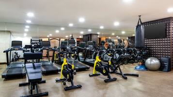 Un gimnasio con diversos equipos de ejercicio, incluyendo cintas de correr, bicicletas estáticas y máquinas de pesas.