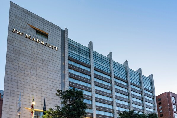 A JW Marriott hotel building with a modern design, featuring a prominent glass facade and a clear sky in the background.