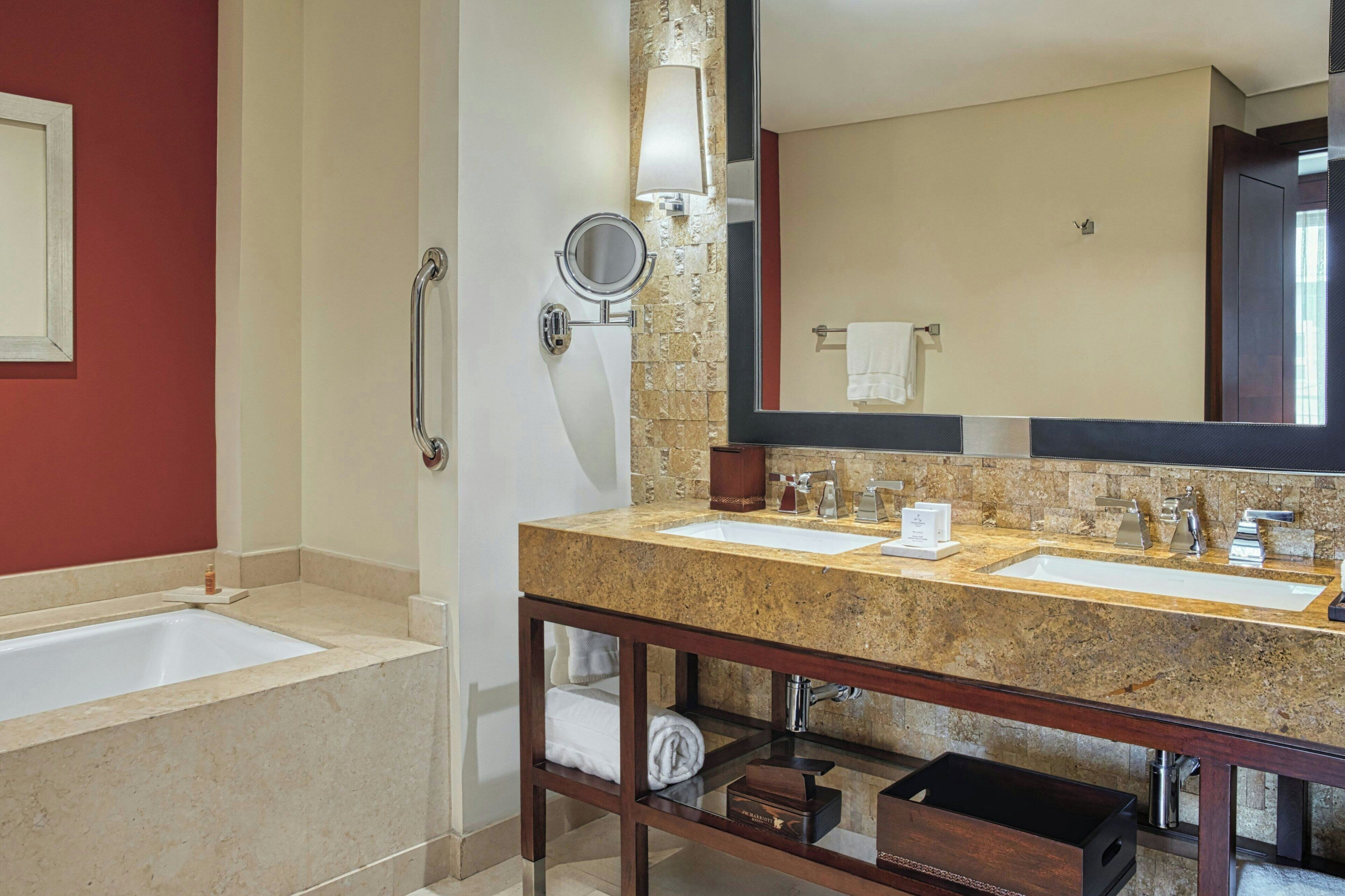 A bathroom with two sinks, a bathtub, a shower, a vanity with a mirror, and a towel rack.