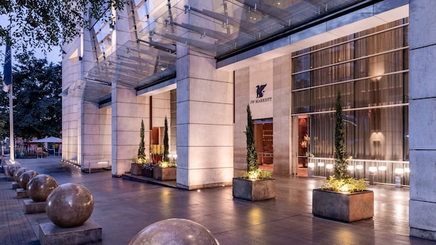 Exterior de un hotel JW Marriott con diseño moderno, grandes ventanales y zonas de estar al aire libre.