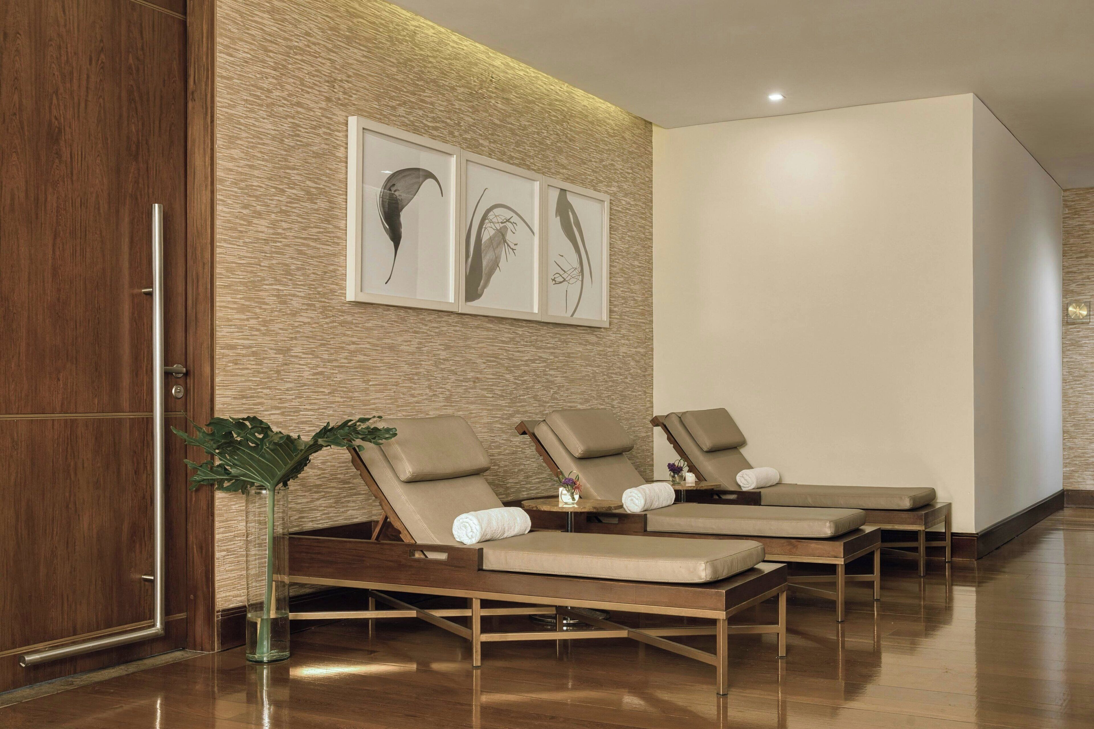 A modern spa area with three reclining chairs, a wooden floor, and a wall-mounted artwork.