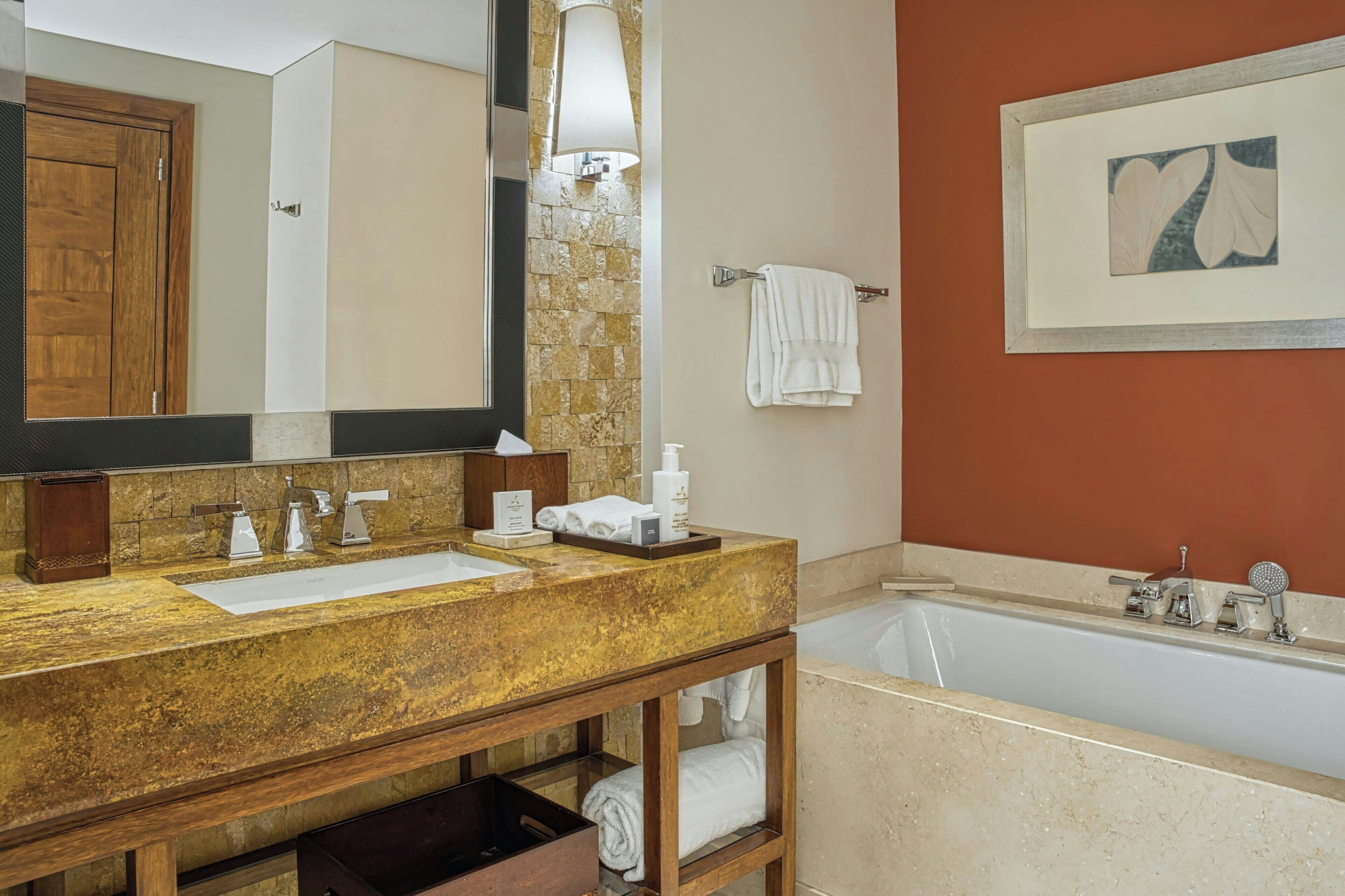 A bathroom with a wooden vanity, two sinks, a large mirror, a bathtub, and a towel rack.