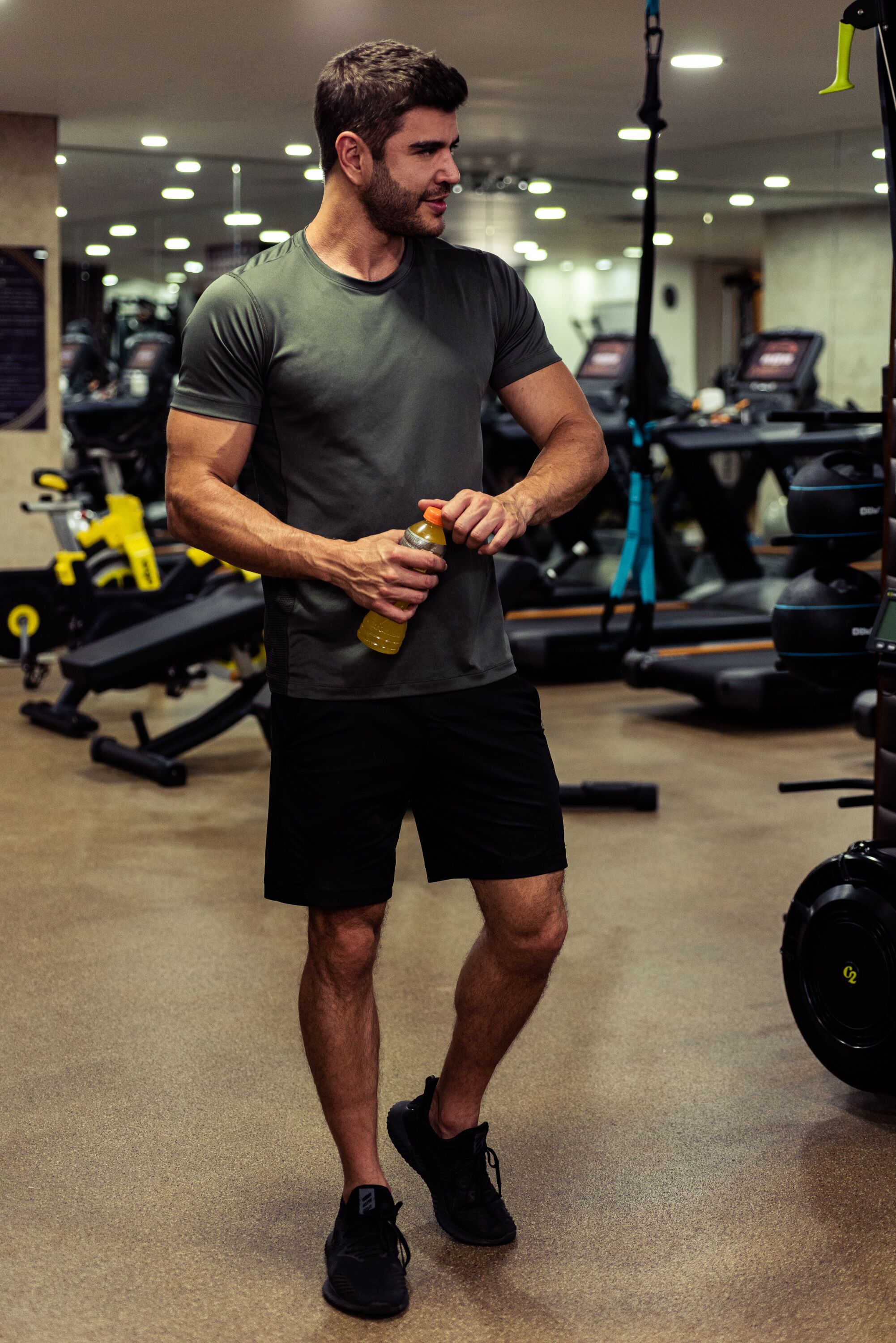 A man in a gym holding a water bottle.