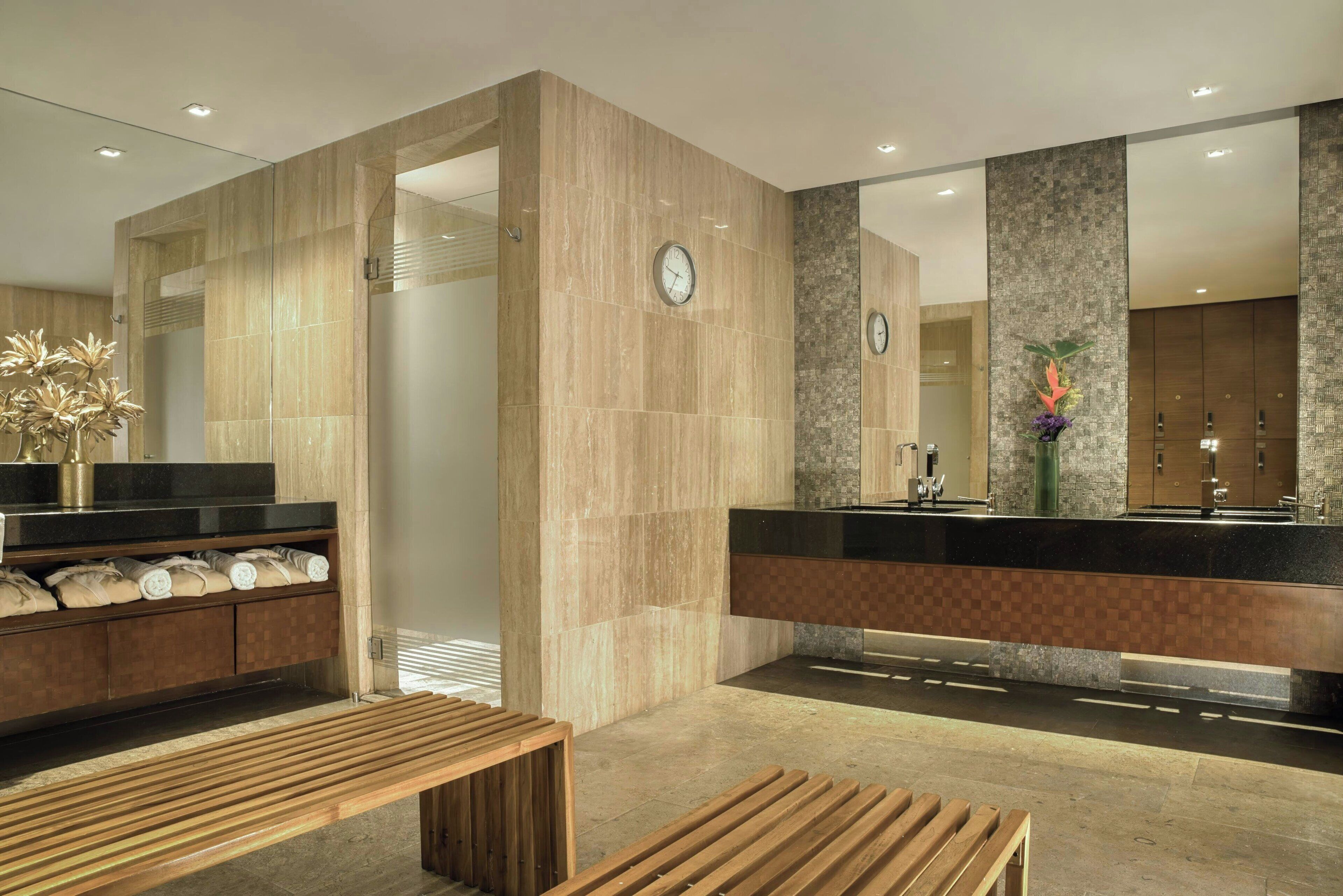 A modern bathroom with a large mirror, a sink, and a bench.
