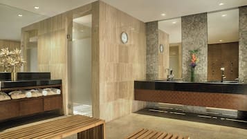 A modern bathroom with a large mirror, a sink, and a bench.