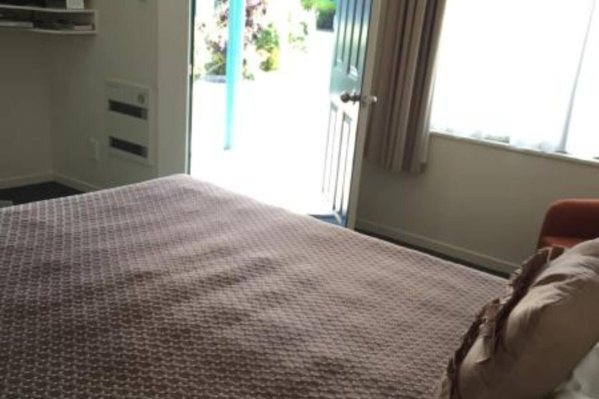 A bedroom with a patterned bedspread, a window with curtains, and a view of the outside.