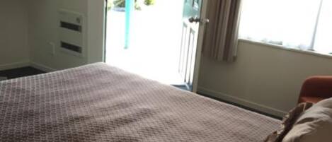 Un dormitorio con una colcha estampada, una ventana con cortinas y vistas al exterior.
