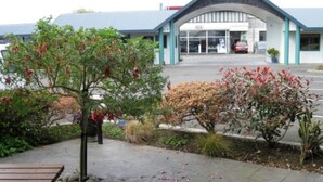 Un bâtiment doté d’une entrée abritée, d’un parking et d’un arbre aux feuilles rouges.