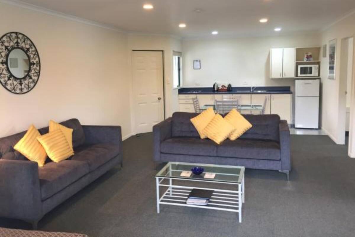 A living room with two sofas, a coffee table, and a kitchen in the background.