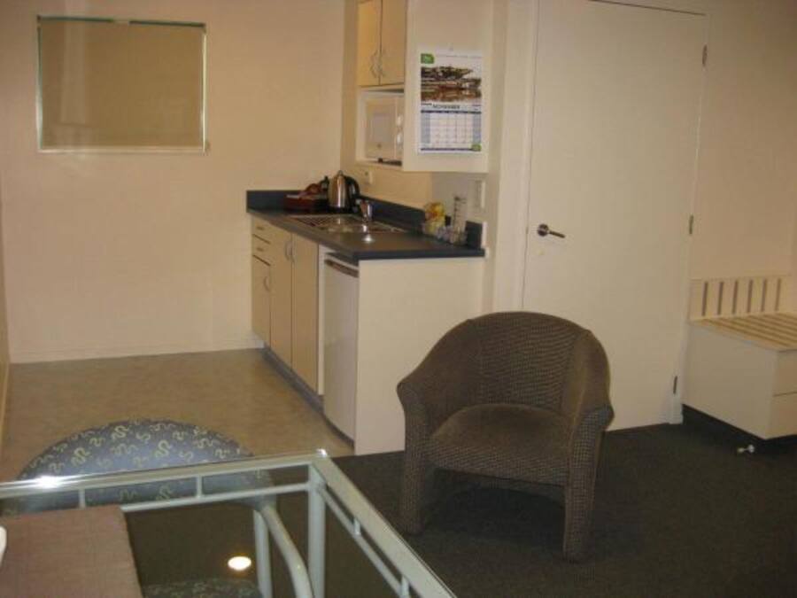 A compact kitchen with a small dining area, a chair, and a glass table.