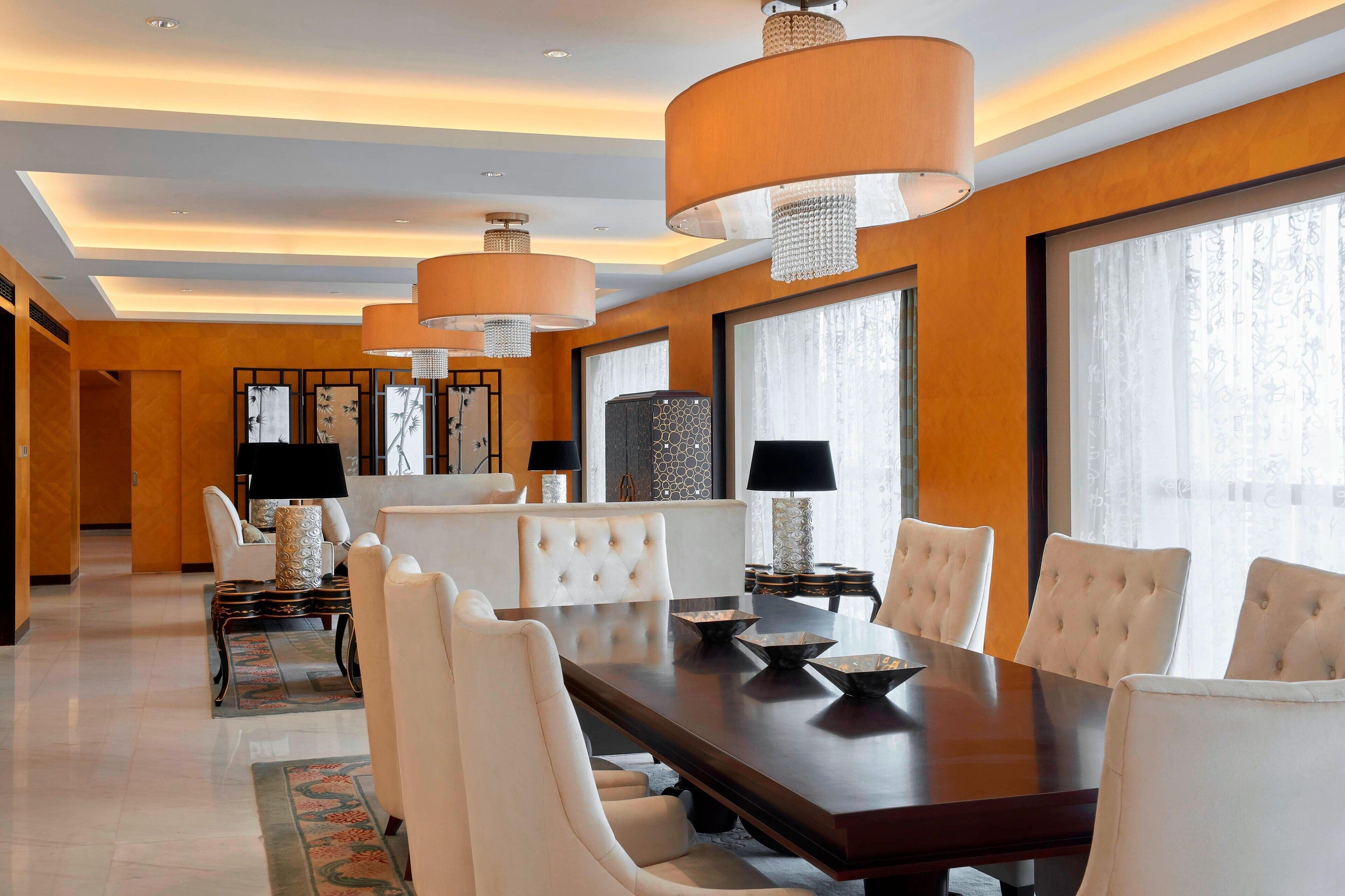 Un comedor amplio con una mesa larga, sillas acolchadas e iluminación colgante.