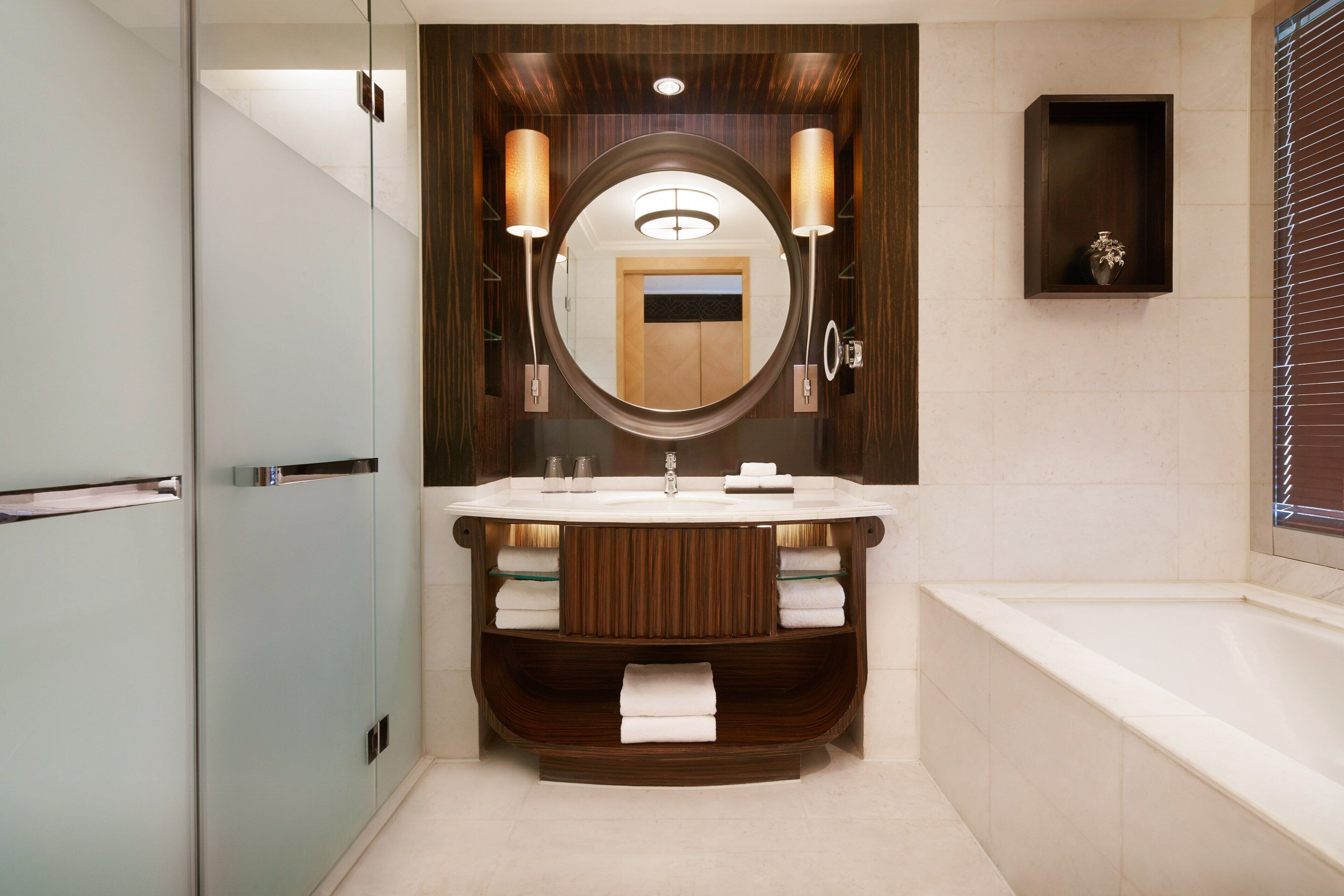 Une salle de bain moderne avec un grand miroir, un lavabo rond et une baignoire intégrée.