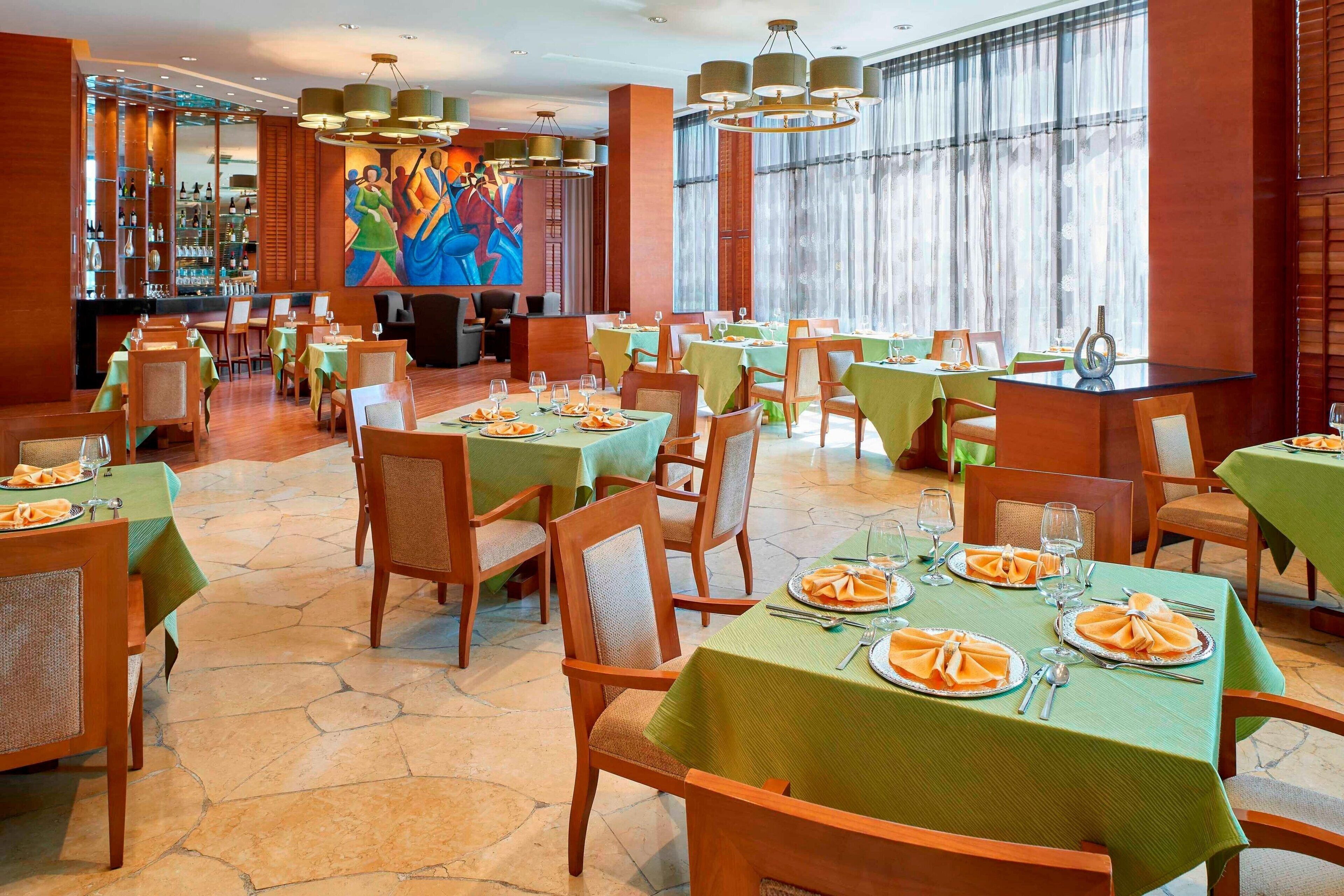 Un restaurante con varias mesas dispuestas para comer, que cuenta con un mural central y una zona de bar.