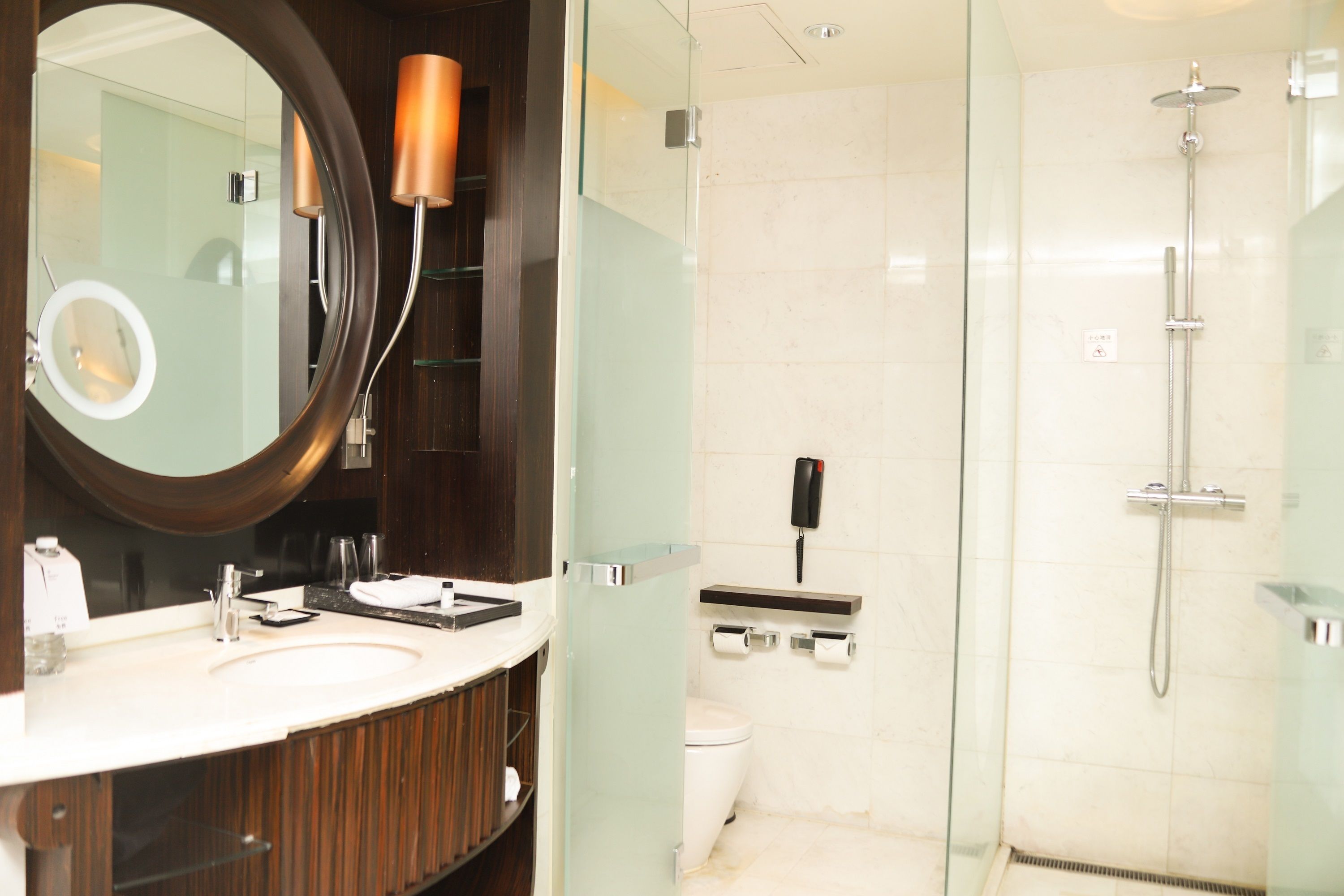 A modern bathroom with a glass shower enclosure, a large mirror, and a vanity with a sink and towel rack.
