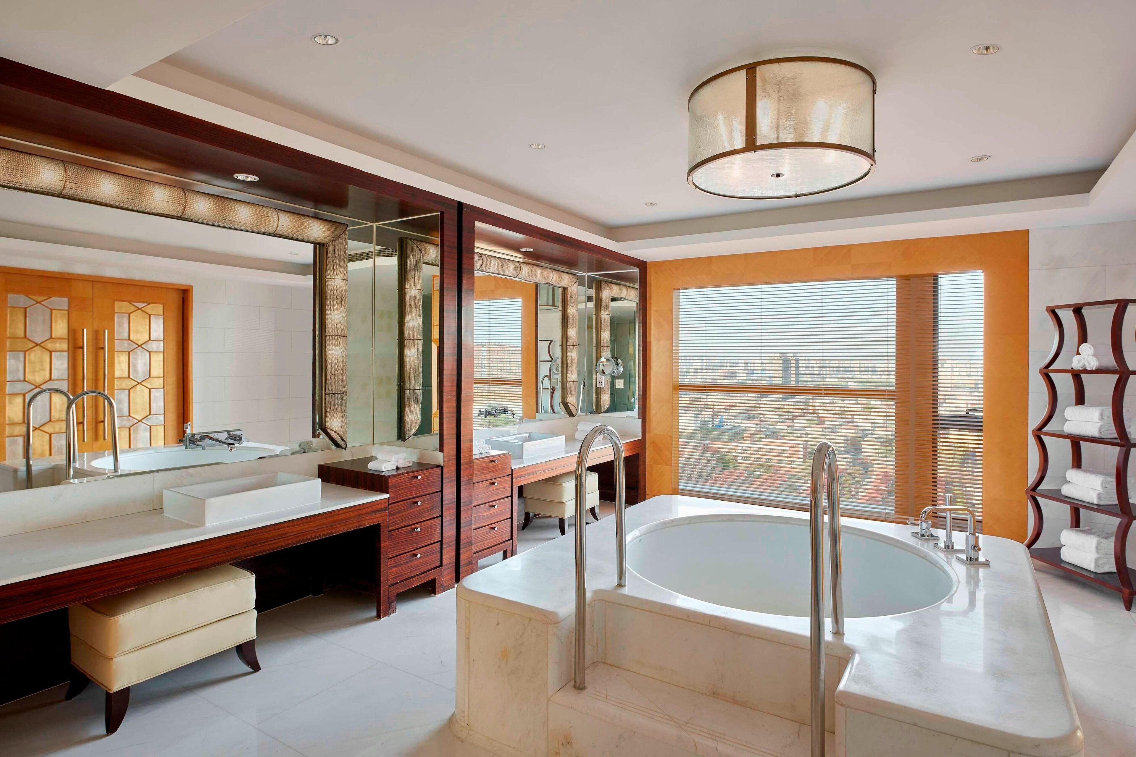A modern bathroom with a large bathtub, double sinks, and a vanity with a mirror.