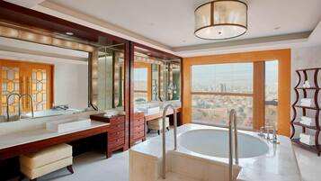 A modern bathroom with a large bathtub, double sinks, and a vanity with a mirror.