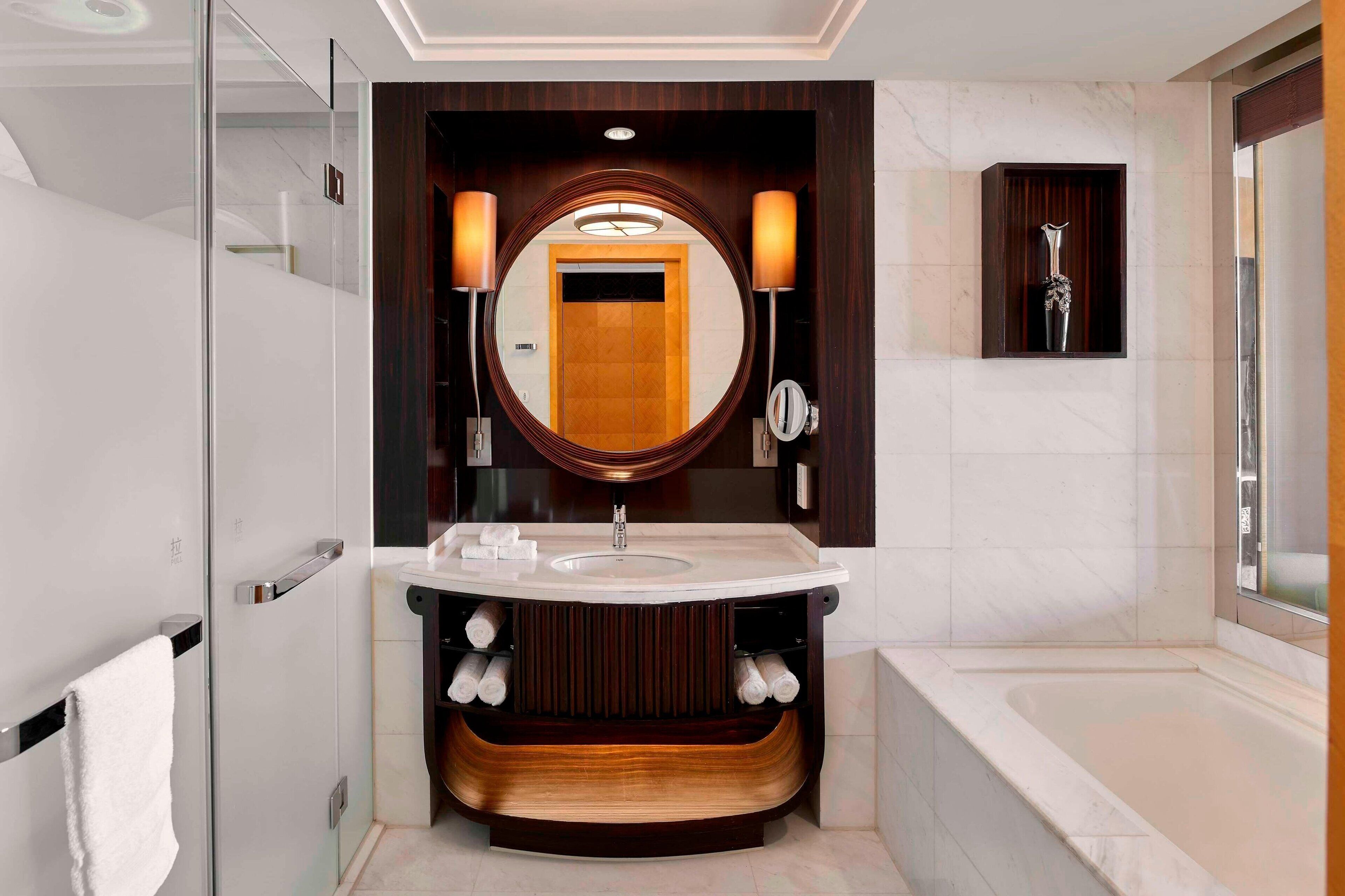 Un baño moderno con un espejo grande, tocador y bañera.