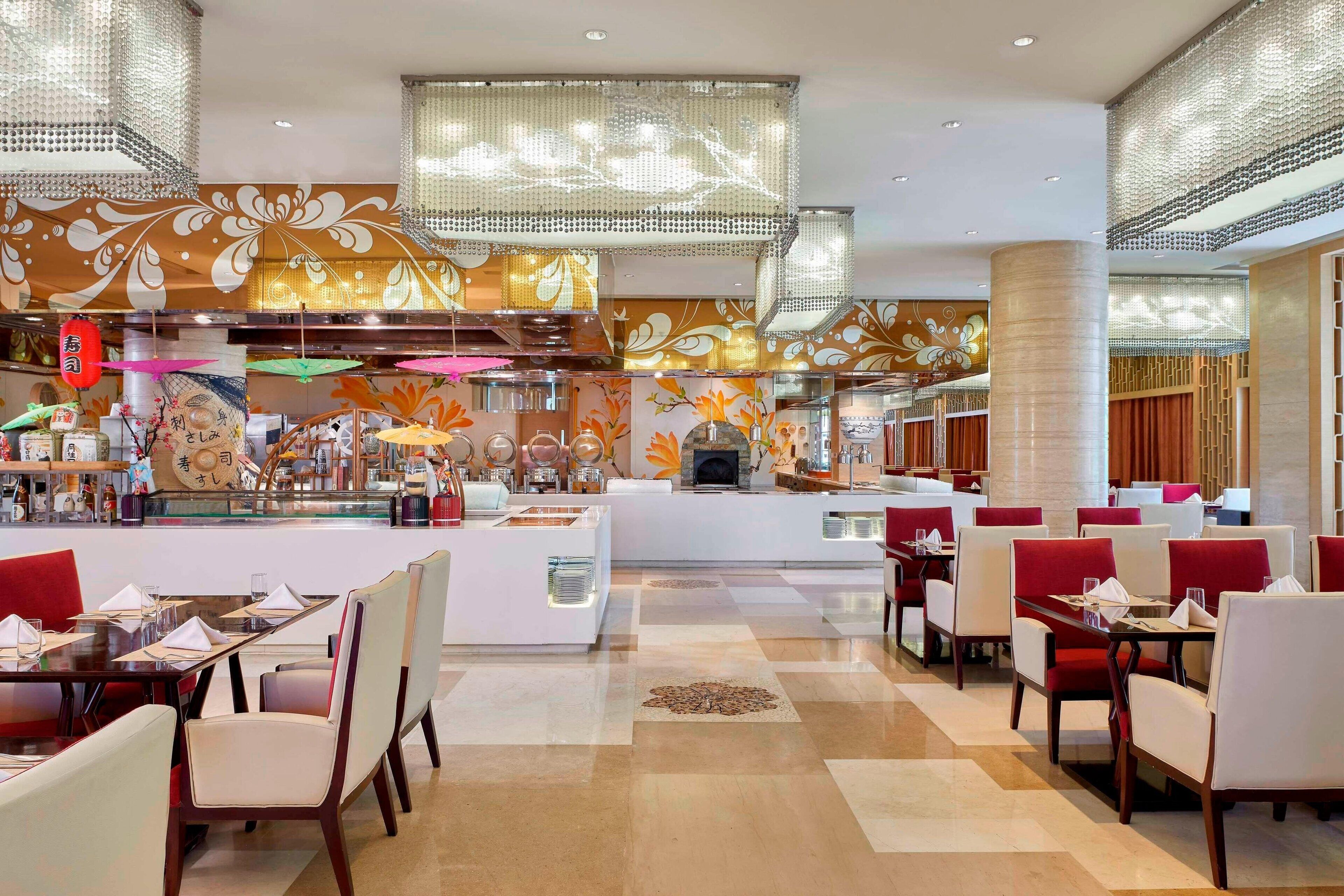 A modern restaurant with a central island, multiple seating areas, and decorative wall panels.