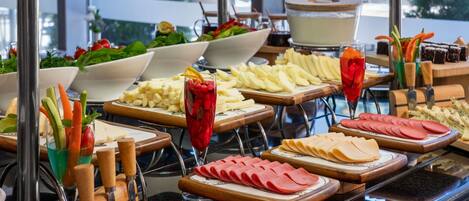 A buffet with various food items including fruits, vegetables, cheeses, and meats.