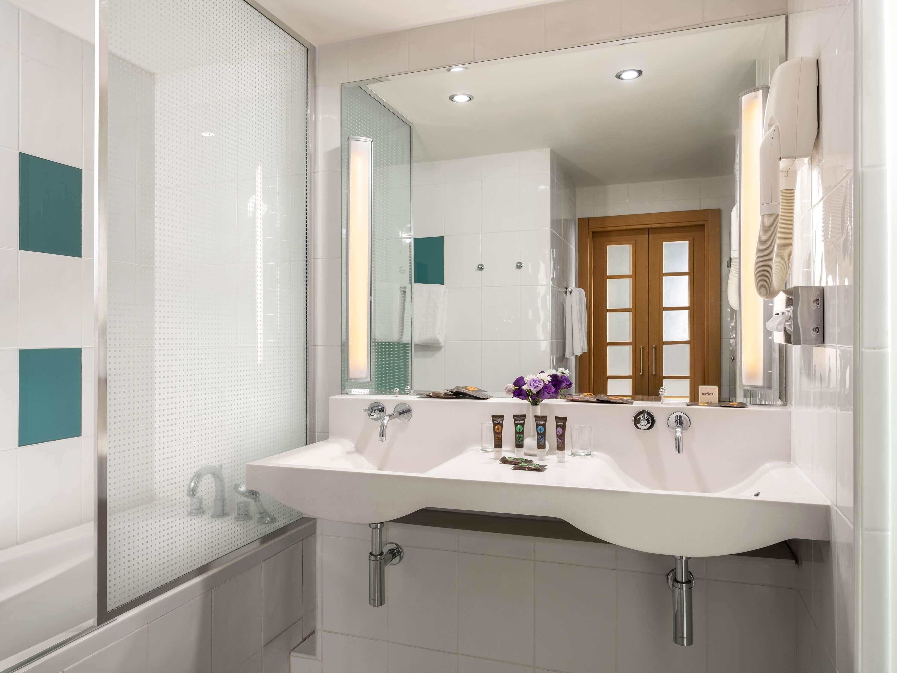 A modern bathroom with two sinks, a large mirror, and a shower enclosure.