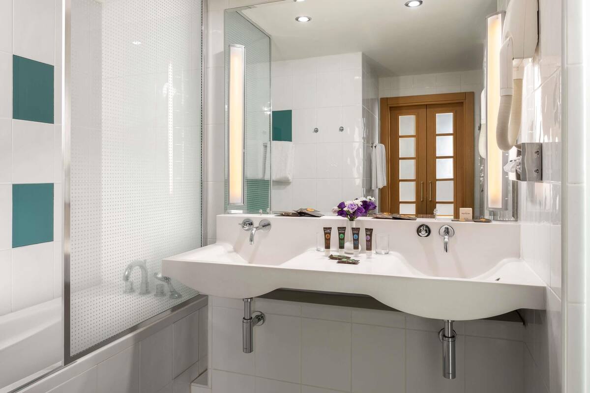 A modern bathroom with two sinks, a large mirror, and a shower enclosure.