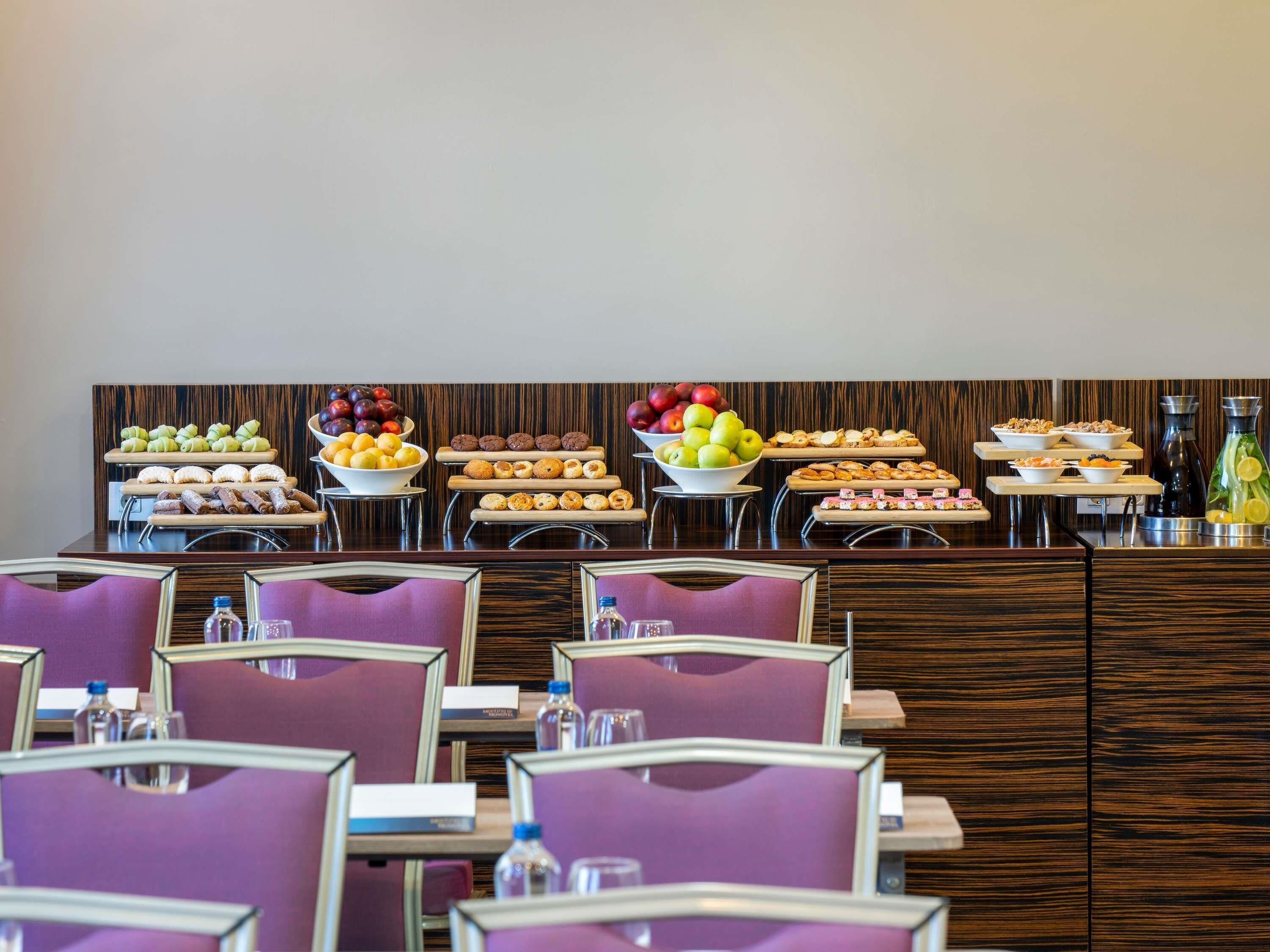 A buffet setup with various food items and a seating area with purple chairs.