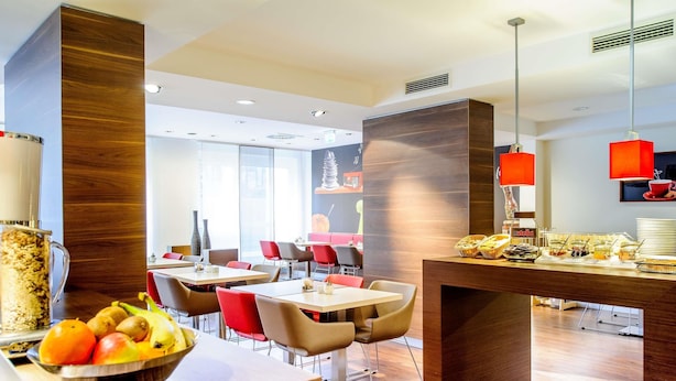 Un comedor de hotel moderno con mobiliario de madera, un bufé con diversas opciones de comida y vistas a la habitación contigua.