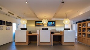 Zona de recepción con tres mostradores, una pantalla de televisión y lámparas colgantes.