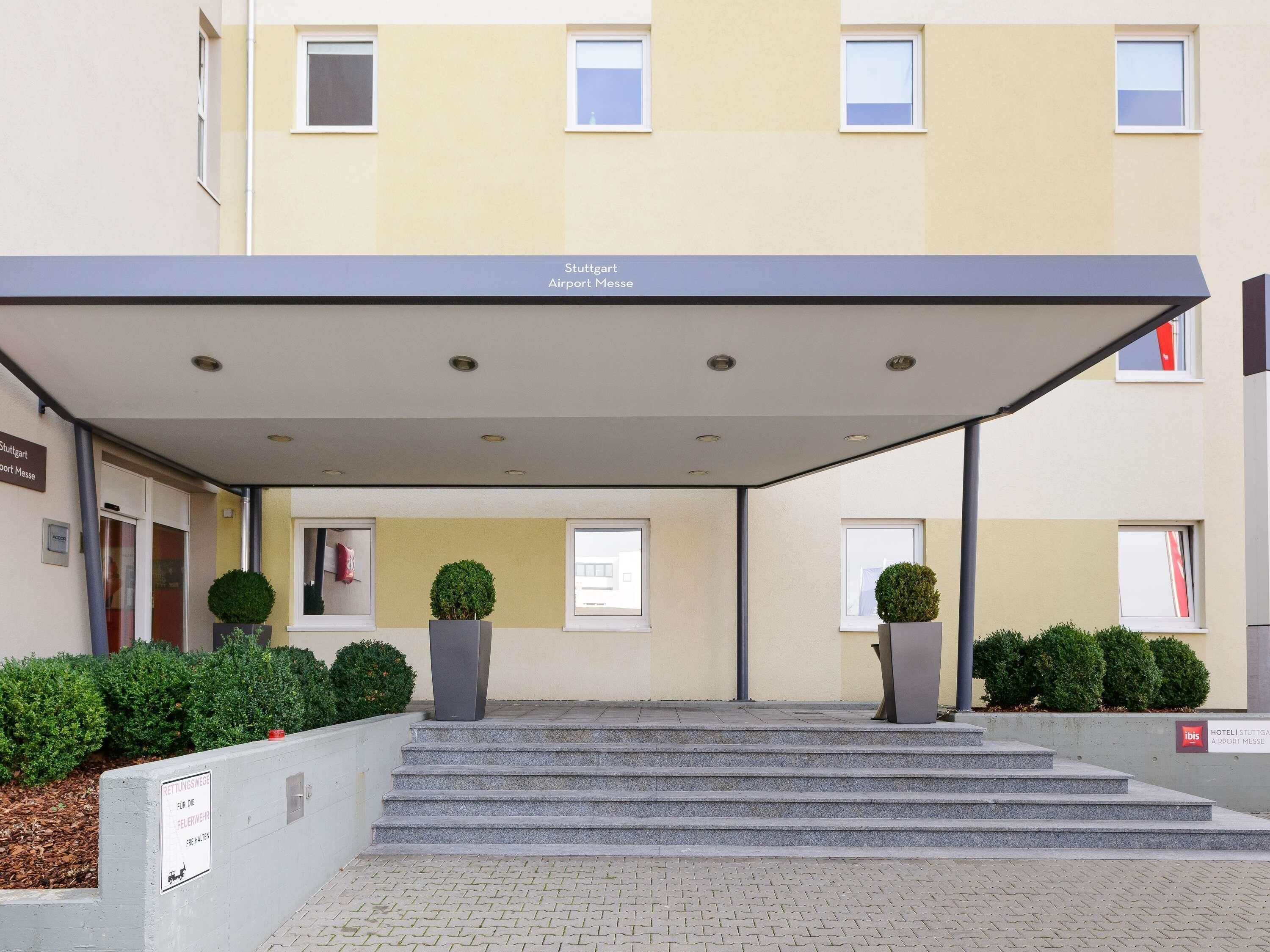 A hotel entrance with a covered walkway, steps, and potted plants.
