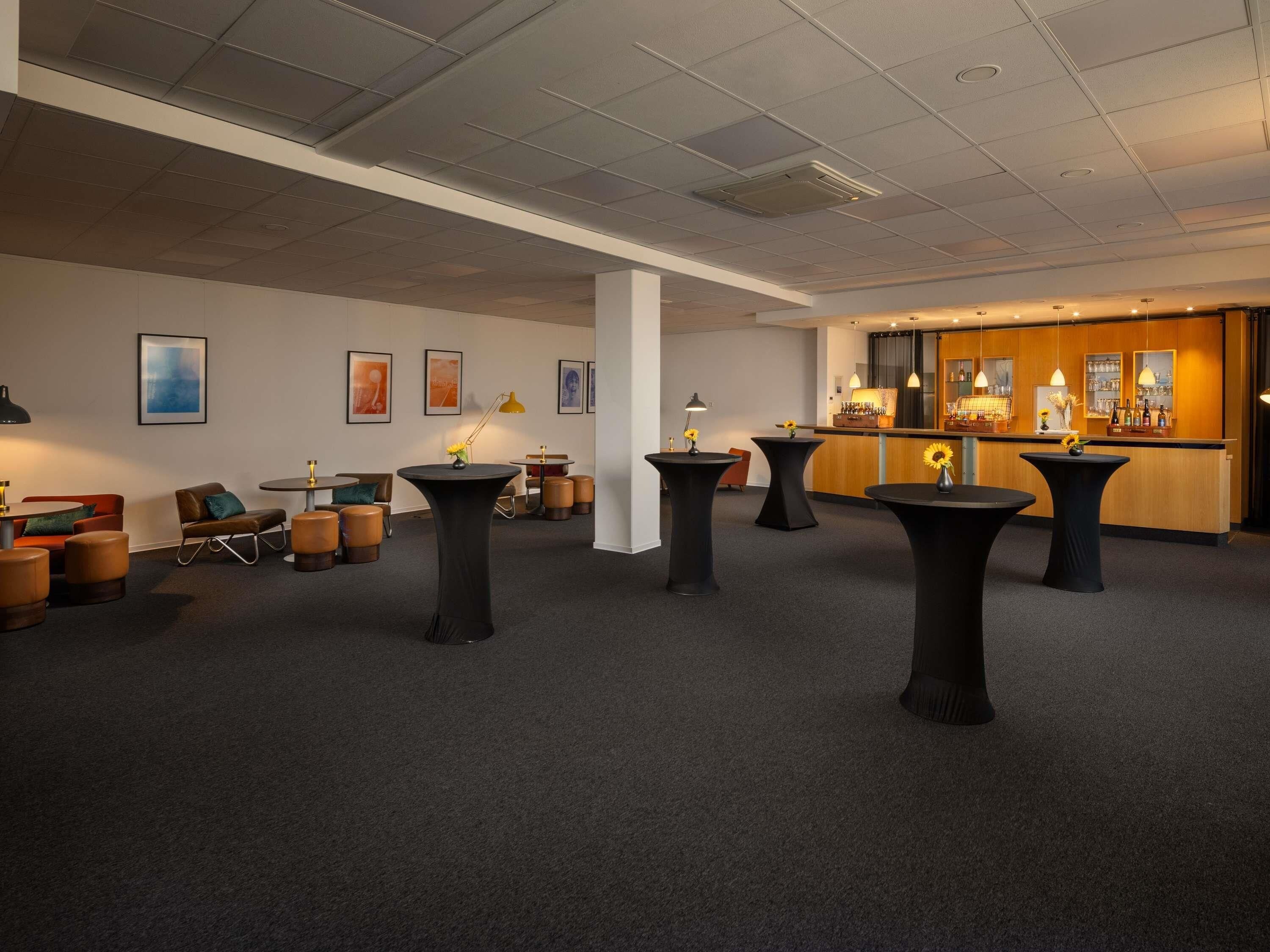 A modern hotel lobby with a bar area, multiple seating arrangements, and artwork on the walls.