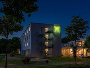 Een modern hotelgebouw met een opvallend 'ibis Styles' bord, meerdere balkons en een goed verlichte ingang.