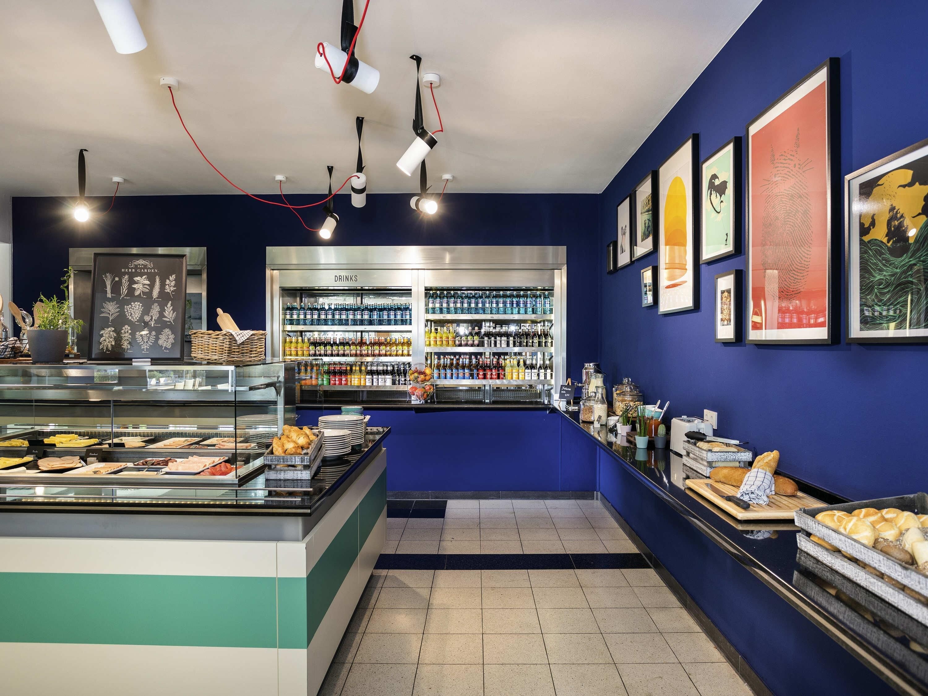 A bakery counter with pastries, a refrigerated drinks section, and framed artwork on the walls.