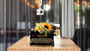 Een oude typmachine met een zonnebloemdecoratie op een houten tafel in een moderne omgeving.