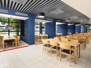 Un comedor espacioso con varias mesas y sillas, amplias ventanas que dejan entrar luz natural, y un diseño de techo moderno.