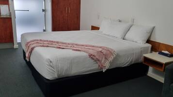A hotel room with a bed, a bedside table, a microwave, and a wardrobe.