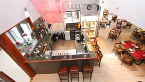 Un restaurante con zona de bar, varias mesas para comer y sillas.