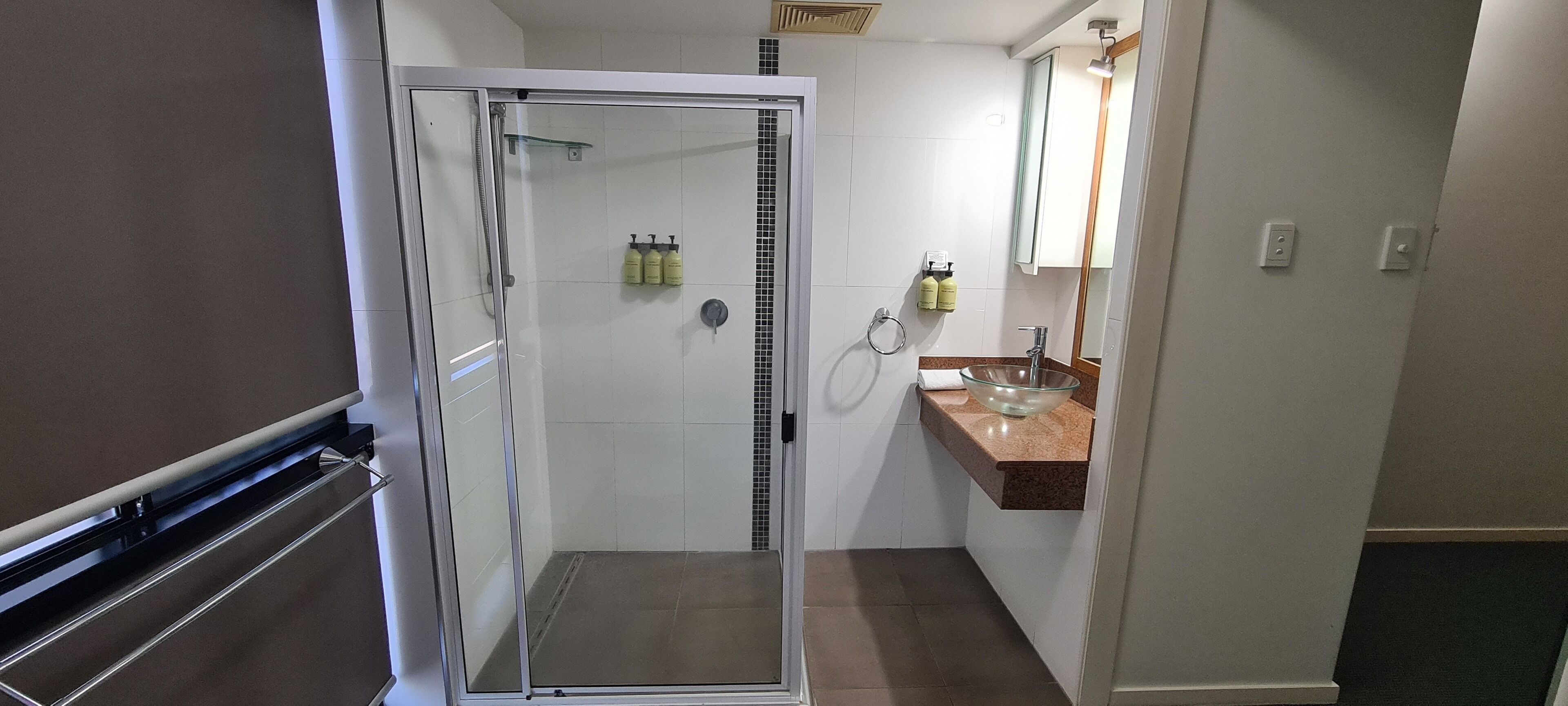 A modern bathroom with a glass-enclosed shower, a marble sink, and a mirror above it.