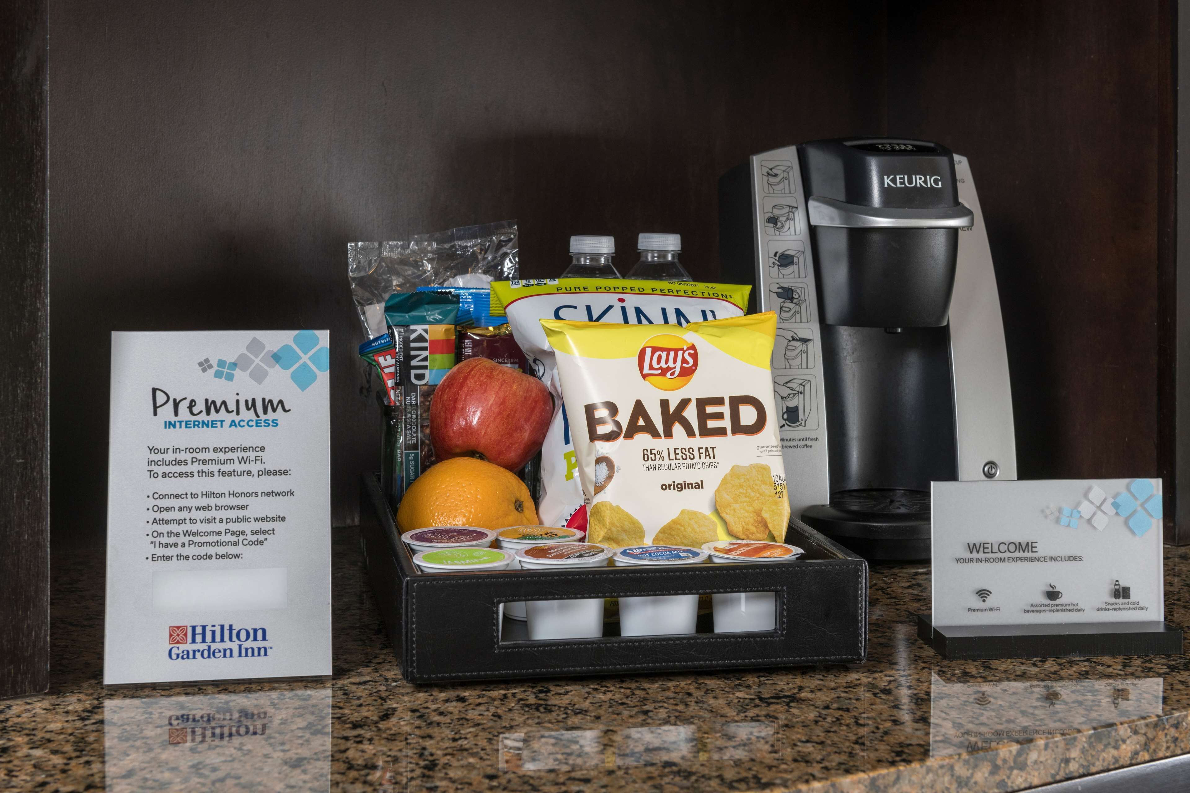 A hotel minibar with snacks, a coffee maker, and a welcome sign.