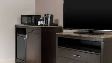 A kitchenette with a microwave, coffee maker, and a flat-screen TV.