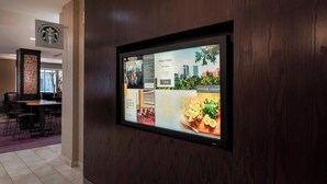 A digital display in a hotel lobby with a Starbucks sign above it. - Courtyard by Marriott Tulsa Downtown (Tulsa)