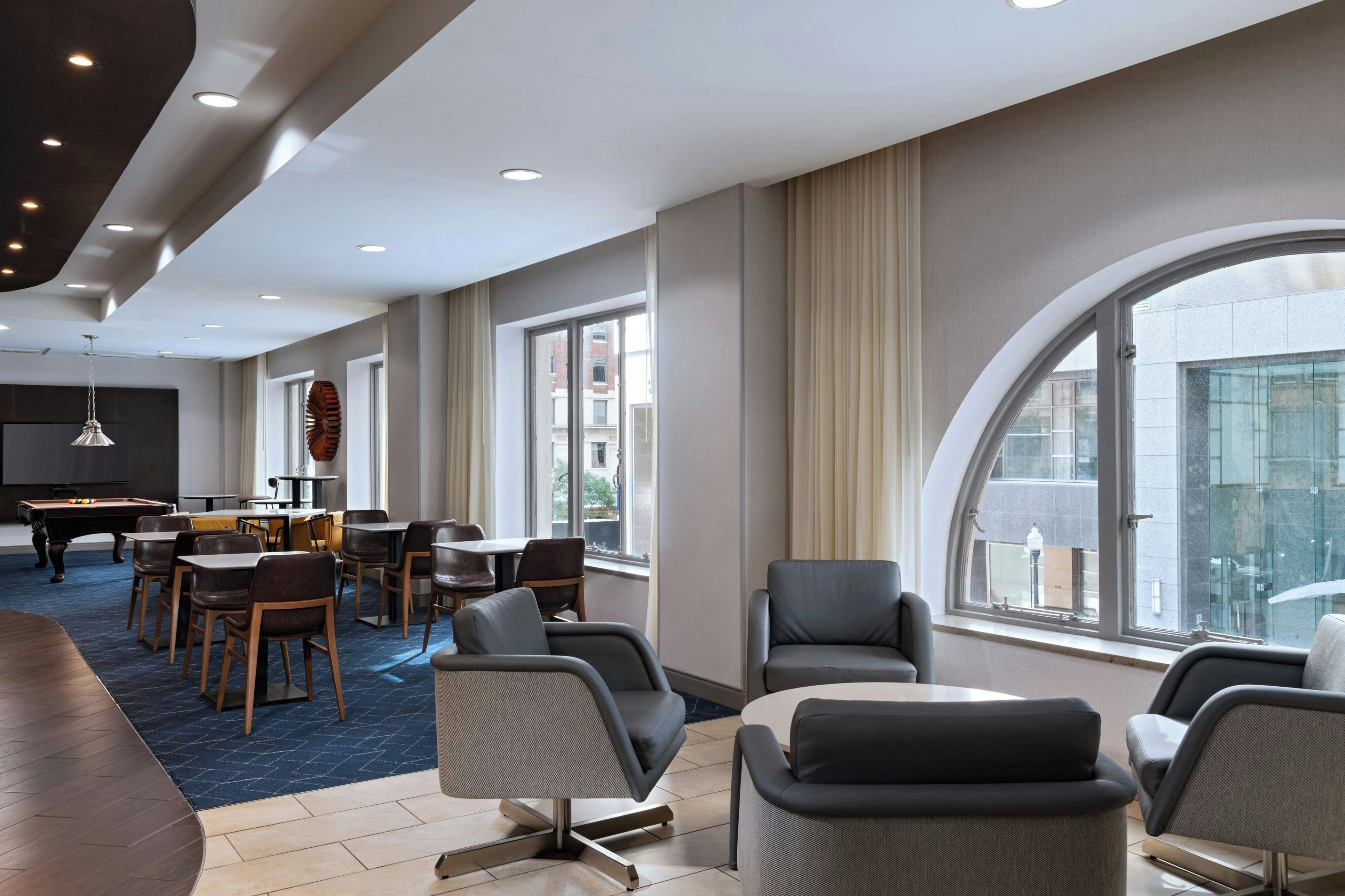 A hotel room with a pool table, dining area, and large windows offering a view.