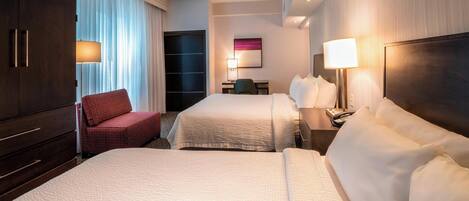 A hotel room with two beds, a desk, a chair, and a wardrobe.