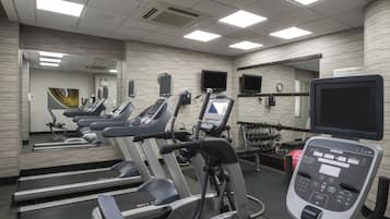 Un gimnasio equipado con cintas de correr, elípticas y una estación de entrenamiento digital.